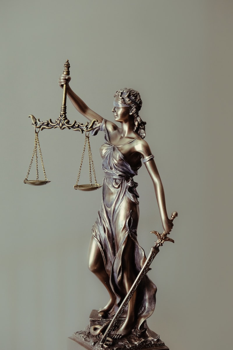Photo by Tingey Injury Law Firm woman in gold dress holding sword figurine